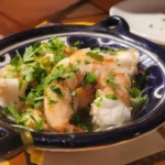 Fresh shrimp dish garnished with chopped herbs in a blue and white ceramic bowl.