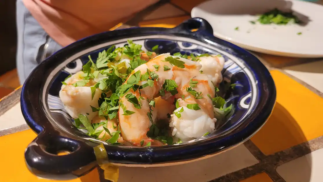 Fresh shrimp dish garnished with chopped herbs in a blue and white ceramic bowl.