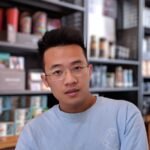 man wearing eyeglasses and blue shirt inside coffee shop